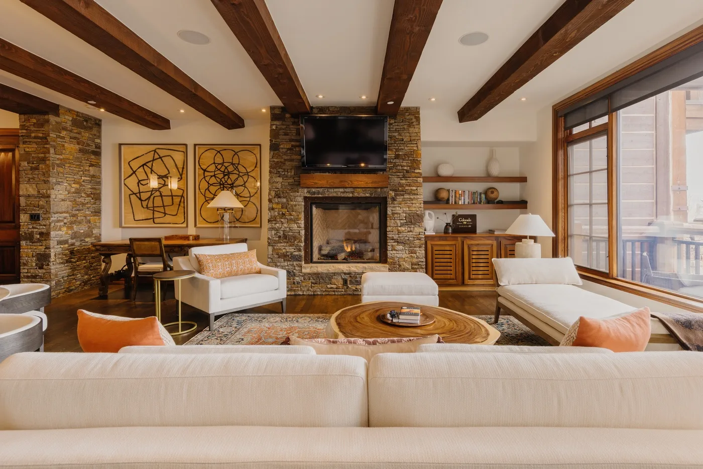 A living room with seating arranged around a stone fireplace and television.