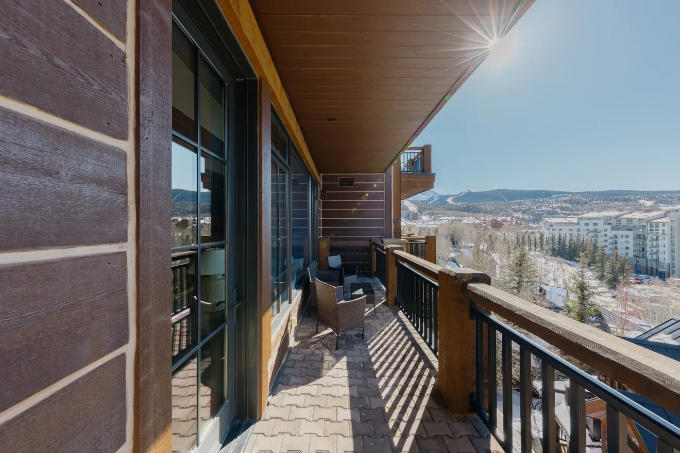A covered balcony with seating overlooks a town and surrounding hills.