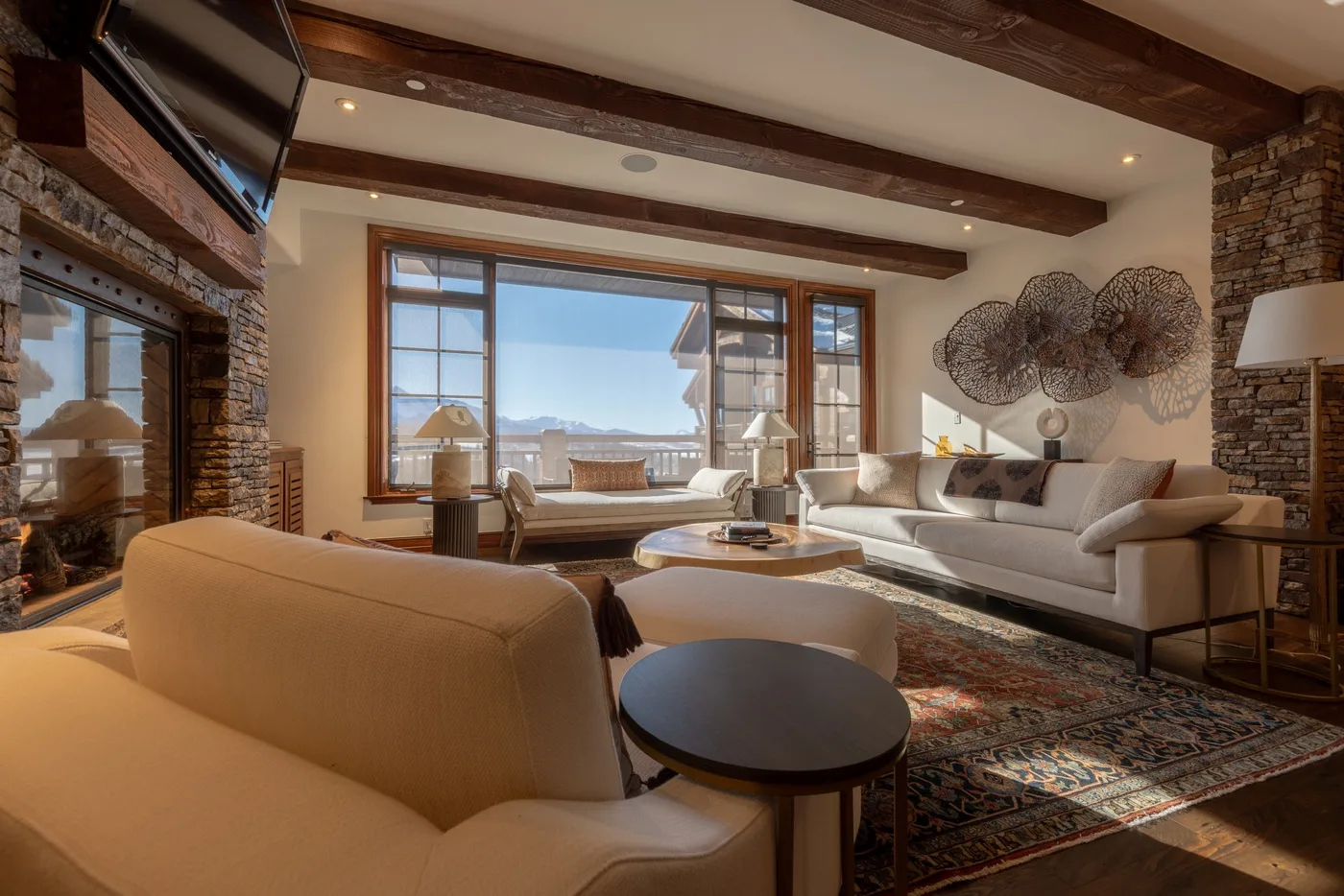 A living room with seating around a coffee table and large windows.