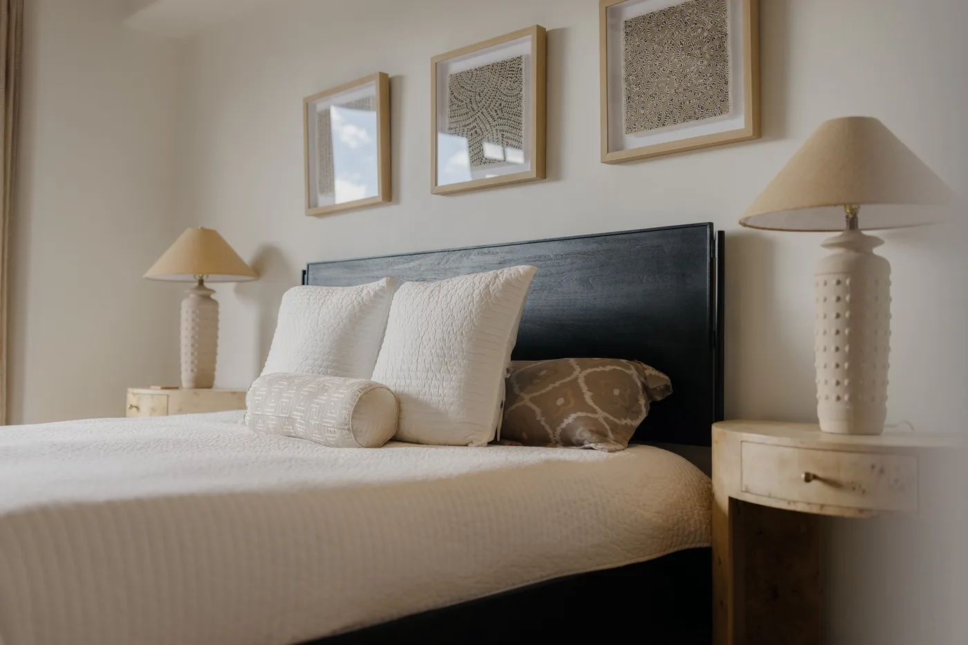 A bedroom with a neatly made bed and framed artwork above the headboard.