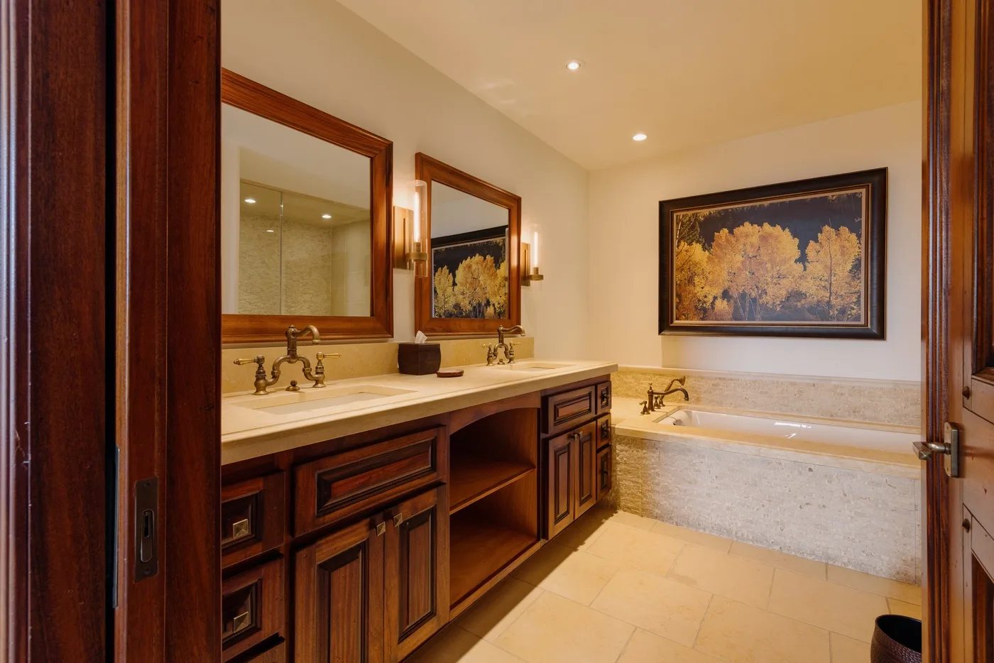 A bathroom with a long vanity, two mirrors, and a built-in bathtub.