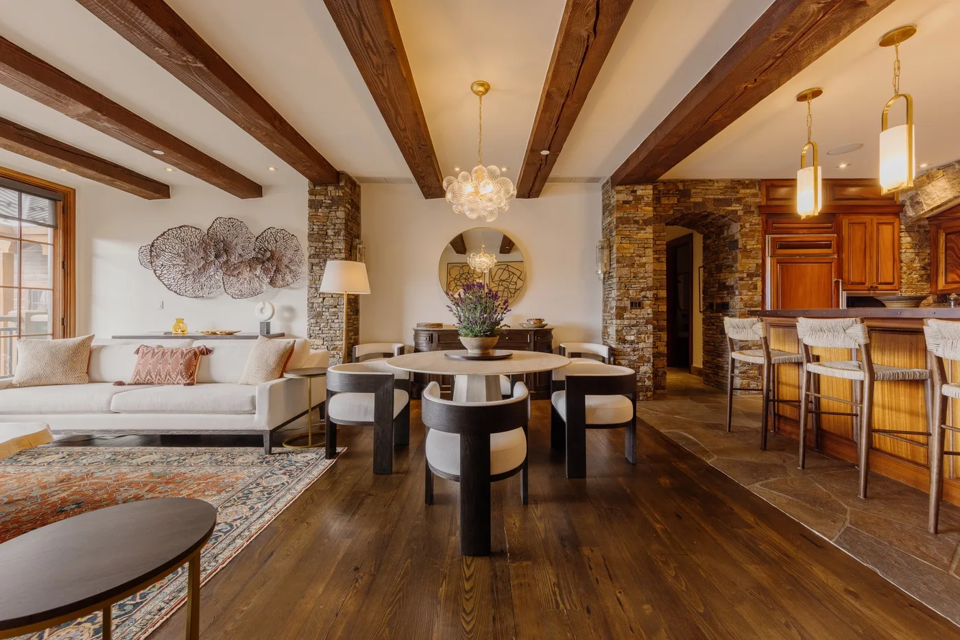 A dining and living area with a round table, seating, and a kitchen bar.