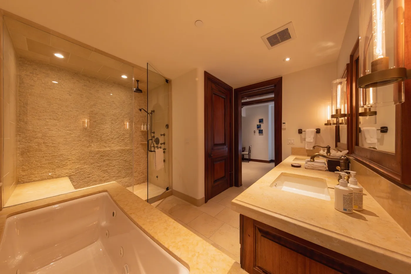 A spacious bathroom with a bathtub, glass shower, and long vanity.