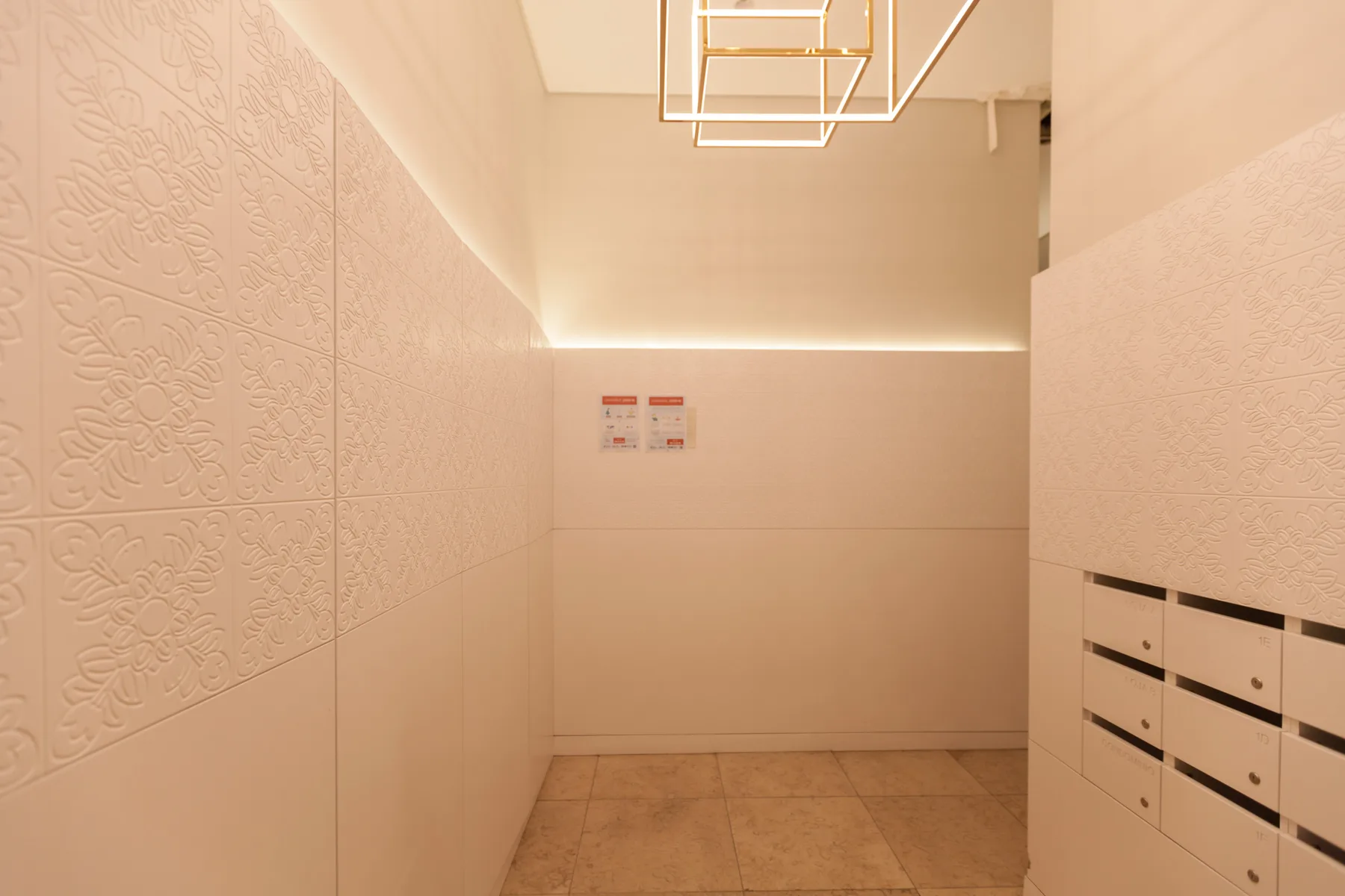 Pasillo de un edificio de apartamentos con paneles decorativos y buzones.