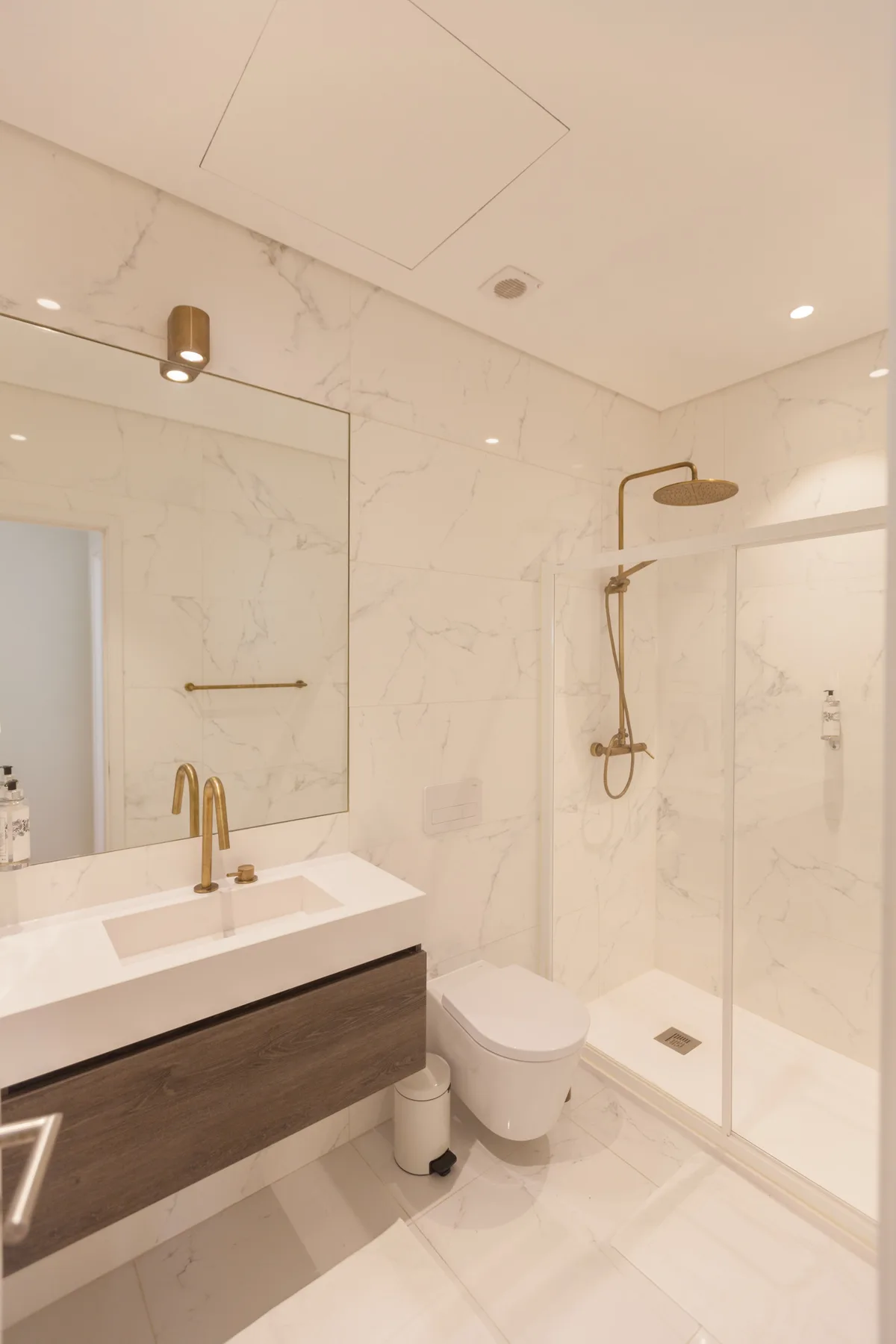 Un baño luminoso con lavabo, inodoro y ducha con mampara de vidrio.