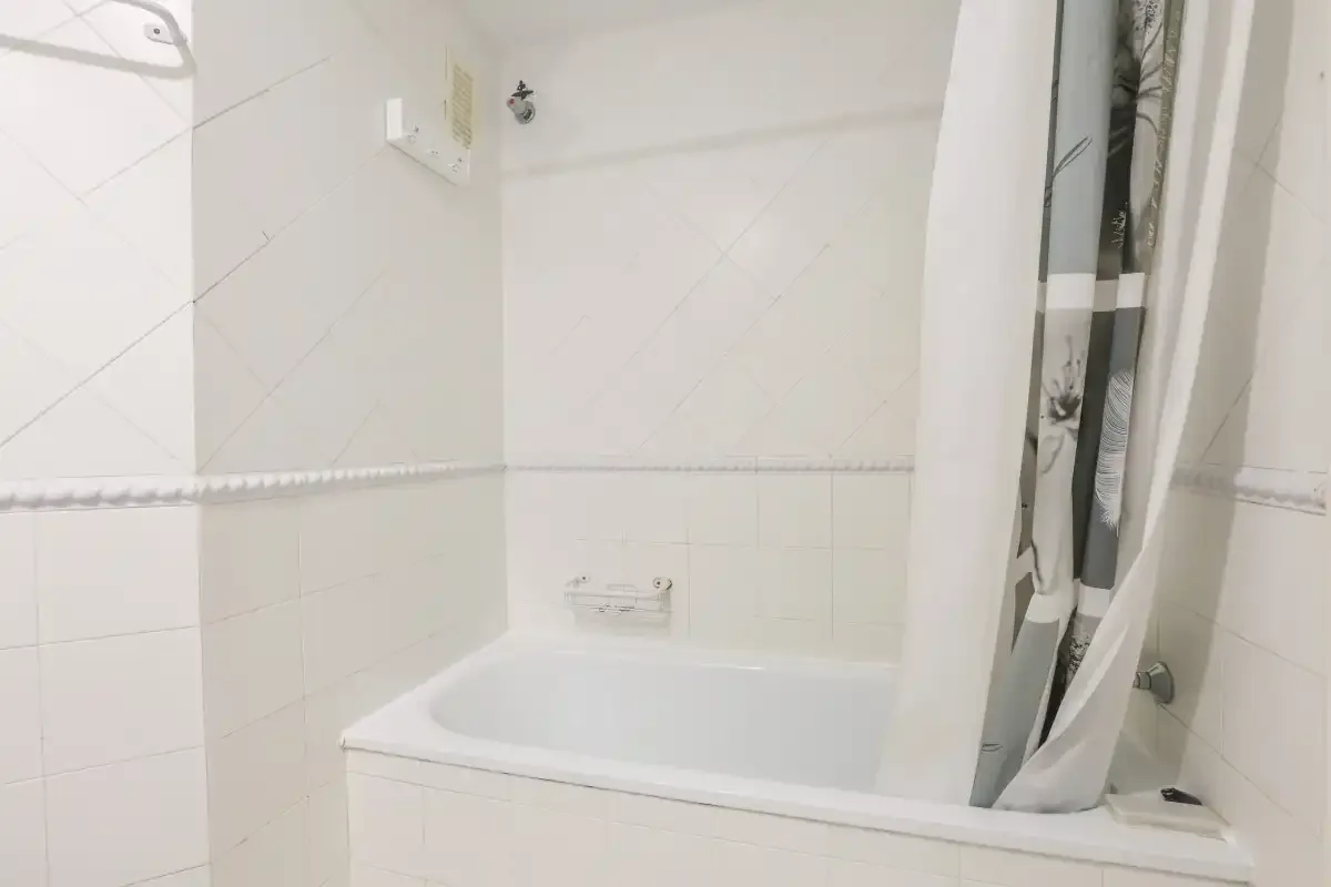 A tiled bathroom with a bathtub and shower curtain.