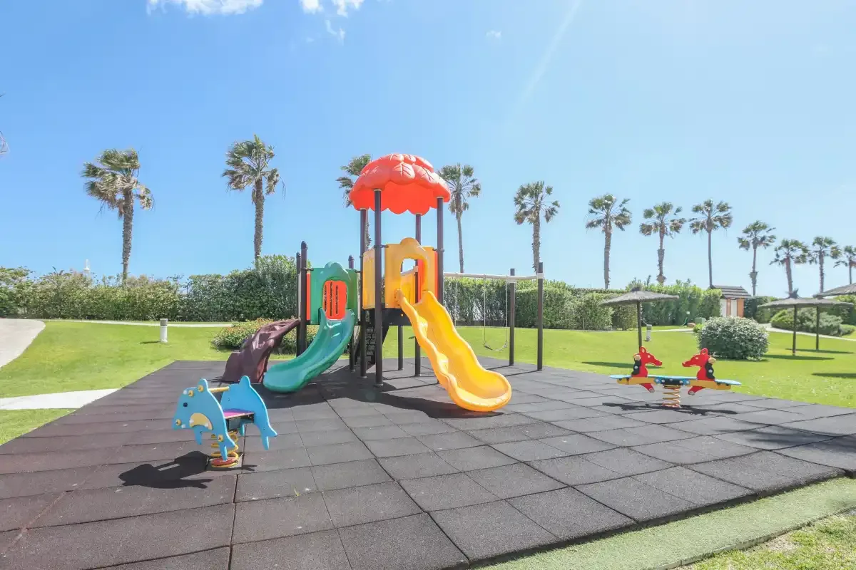 A playground with colorful slides and play equipment on a rubberized surface.