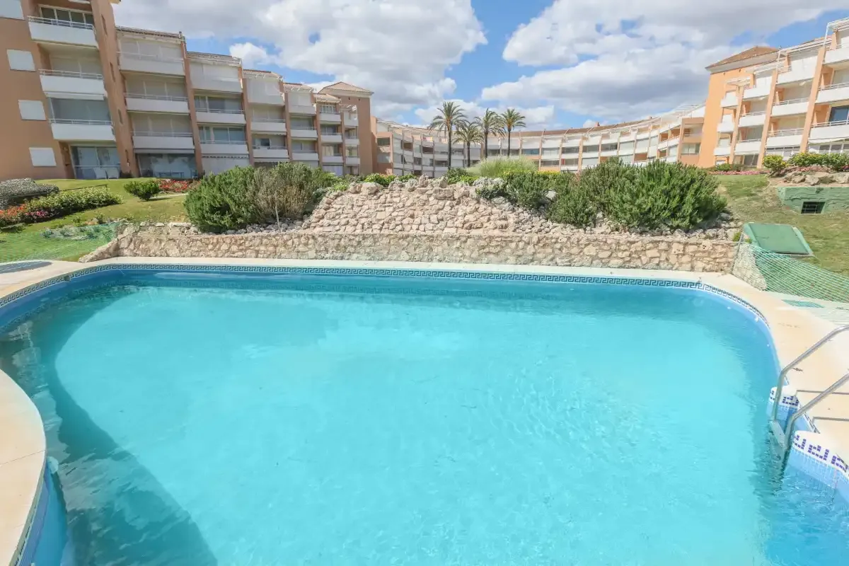 A swimming pool in a landscaped courtyard surrounded by apartment buildings.