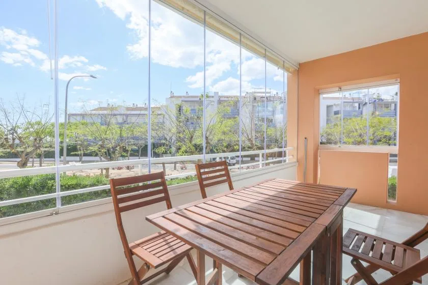 A dining area with a wooden table and chairs beside large windows.