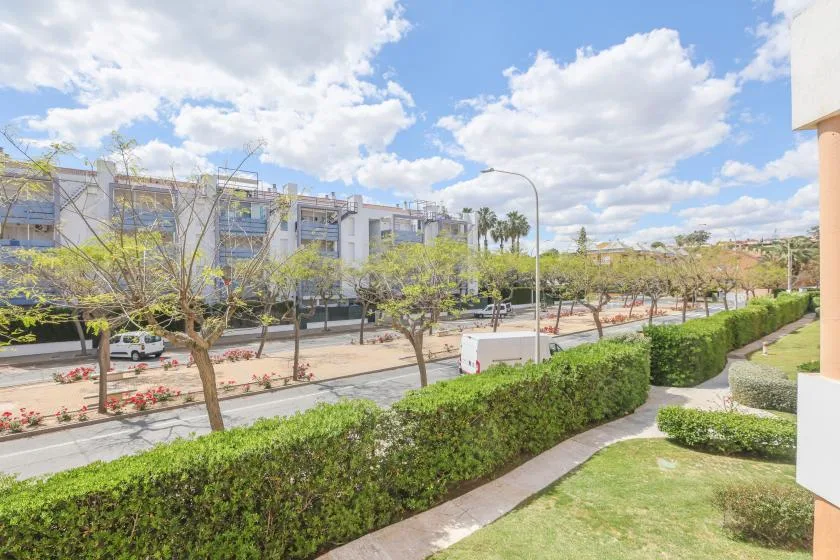 A landscaped outdoor area overlooks a tree-lined street and modern buildings.