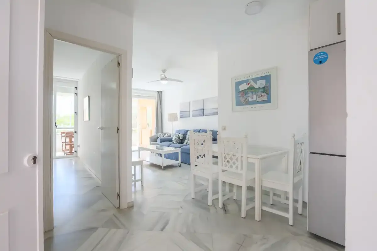 A bright living and dining area with blue seating and a white dining table.