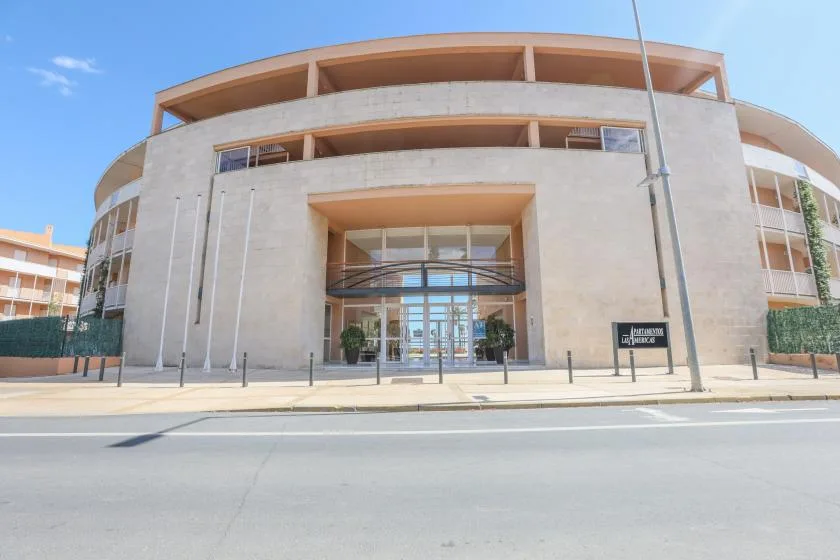 A modern building with a glass entrance faces a wide paved street.