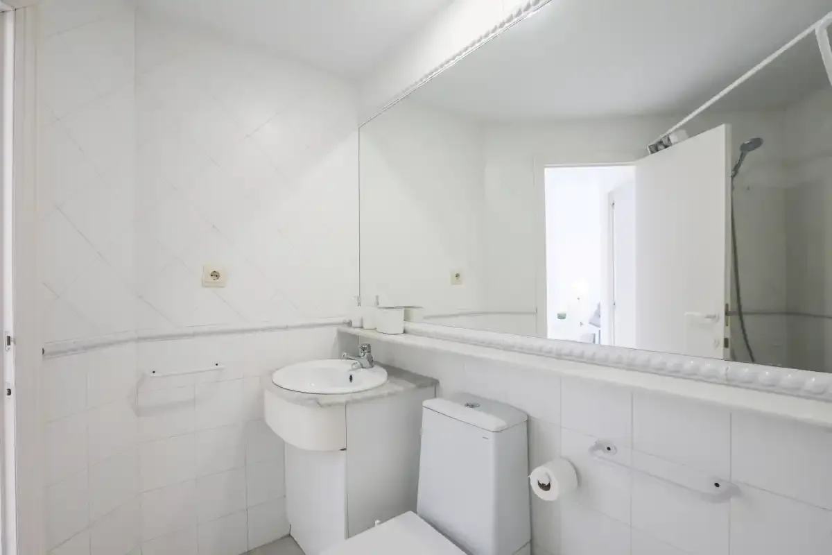 A bright bathroom with a sink, toilet, and large wall mirror.