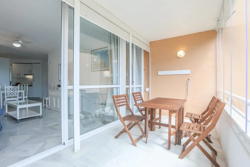 A dining area with a wooden table and chairs beside large glass doors.