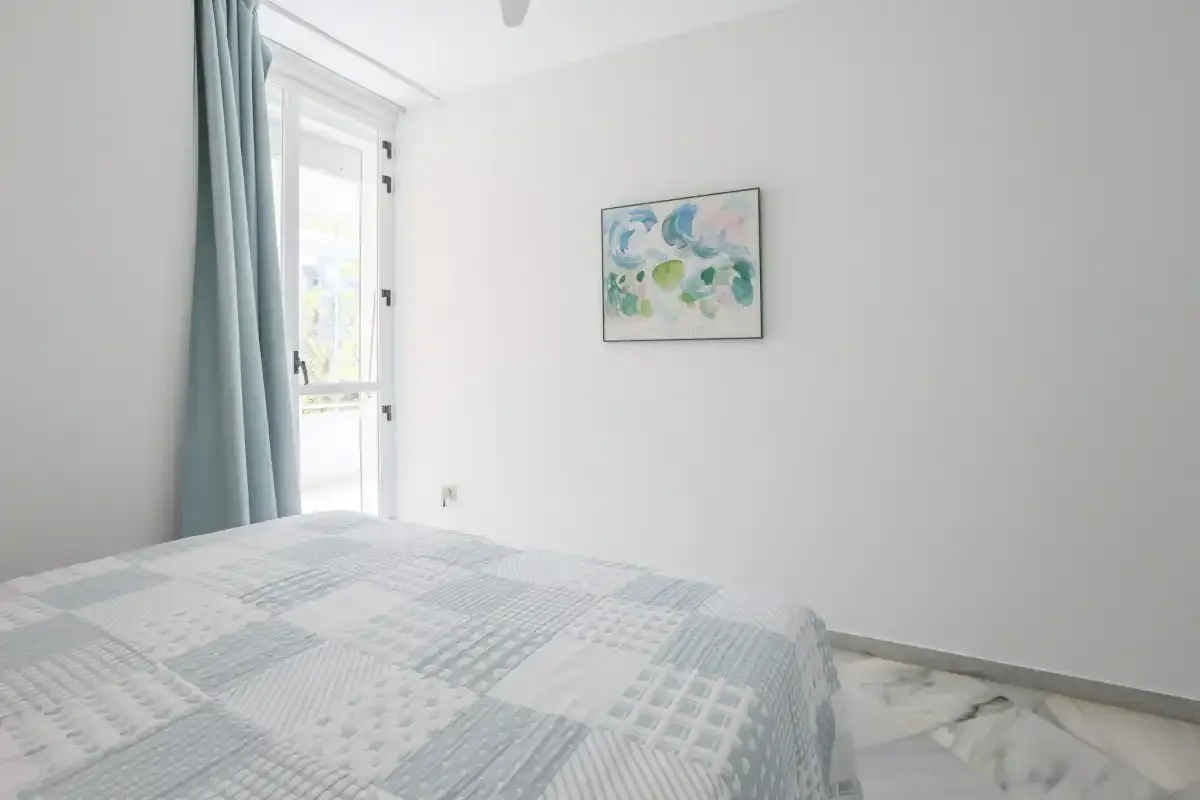 A bright bedroom with a patterned bedspread and a glass door.