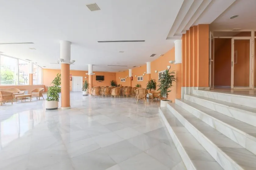 A bright lobby with seating, plants, and steps leading to a raised entrance.