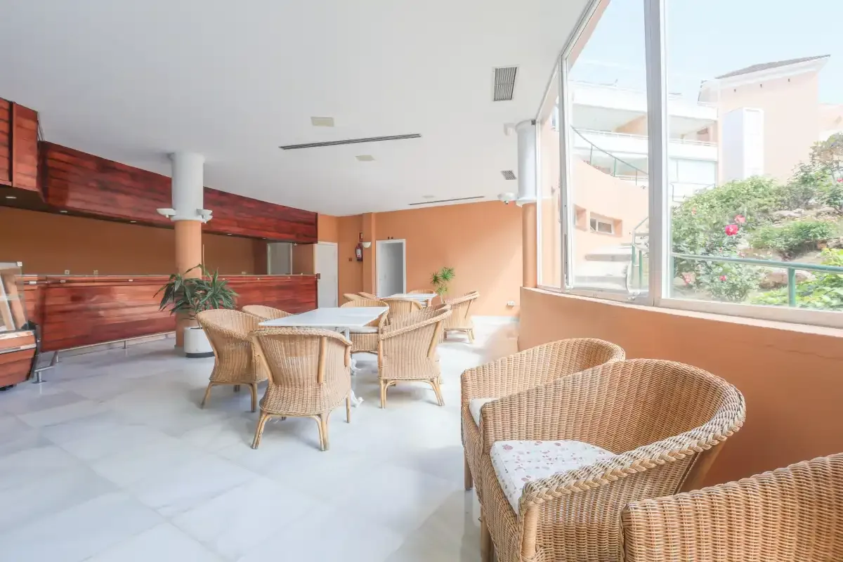 A bright lounge with wicker seating beside large windows.