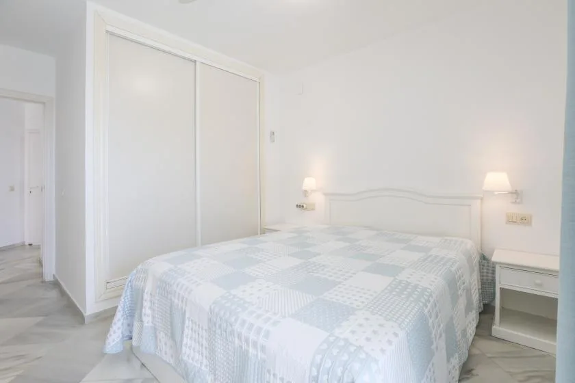A bright bedroom with a bed, bedside tables, and a large closet.