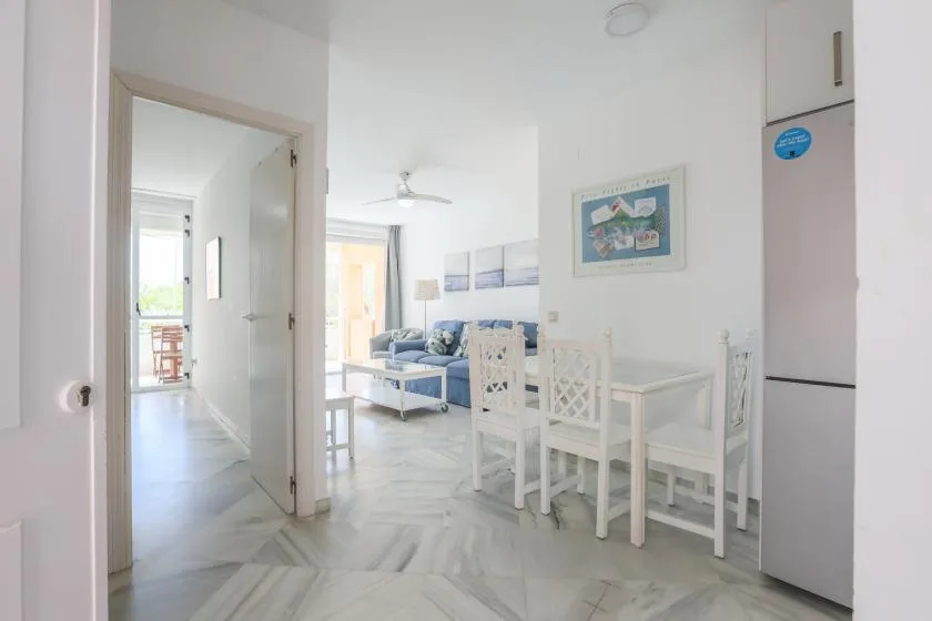 A bright living and dining area with a blue sofa and white dining furniture.