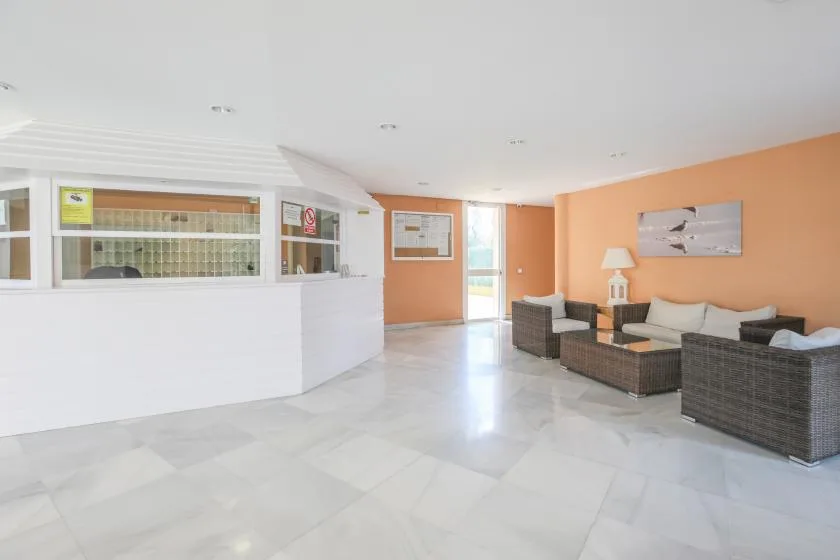 A reception area with a white counter and a seating area along the orange wall.