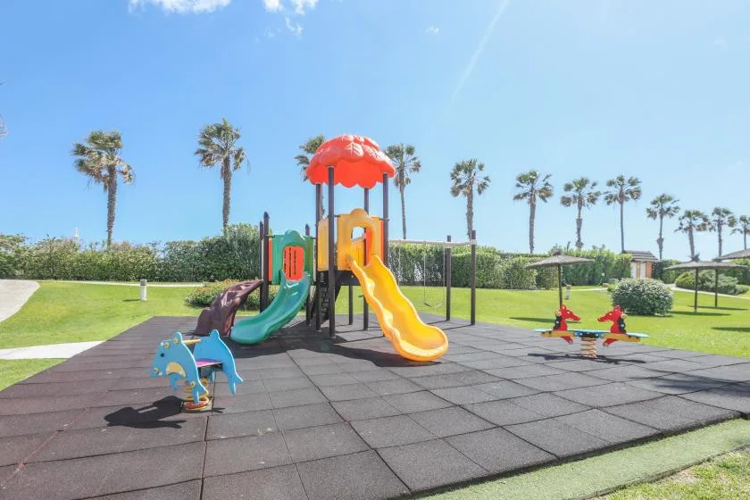 A colorful playground with slides and play equipment on a sunny lawn.
