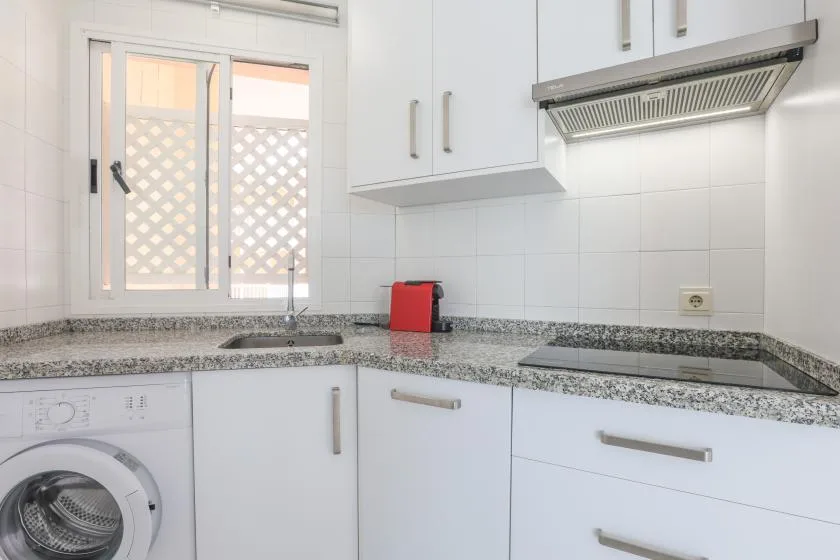 A bright kitchen with white cabinets, a countertop, and a window.