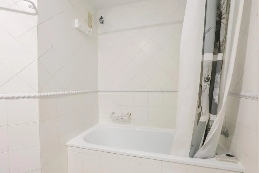 A tiled bathroom with a bathtub and shower curtain.