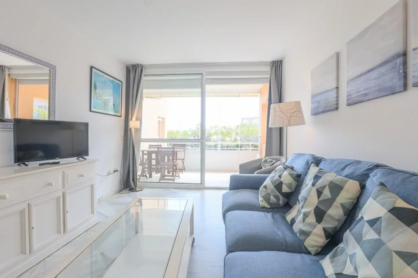 A bright living room with a television and seating beside large glass doors.