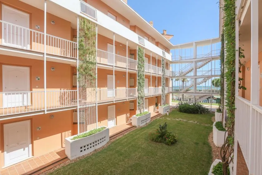 An apartment building courtyard with balconies, planted walls, and a small lawn.