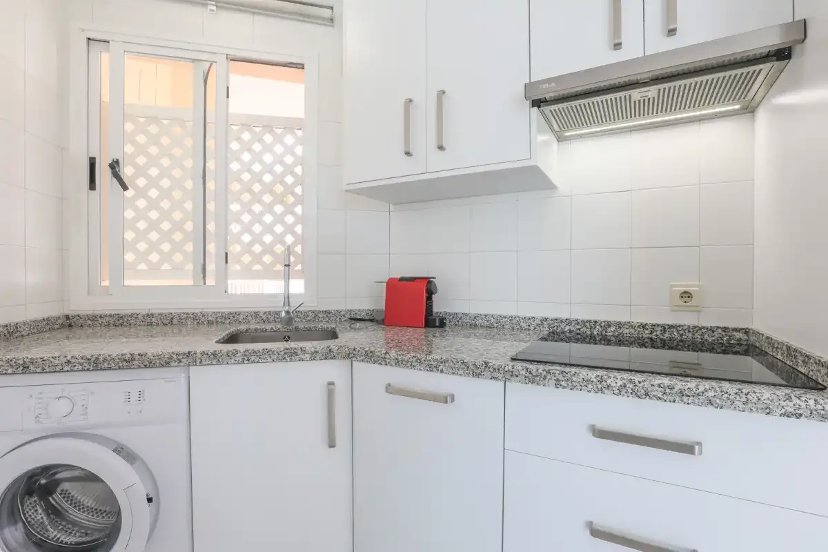 A bright kitchen with white cabinets and a countertop.