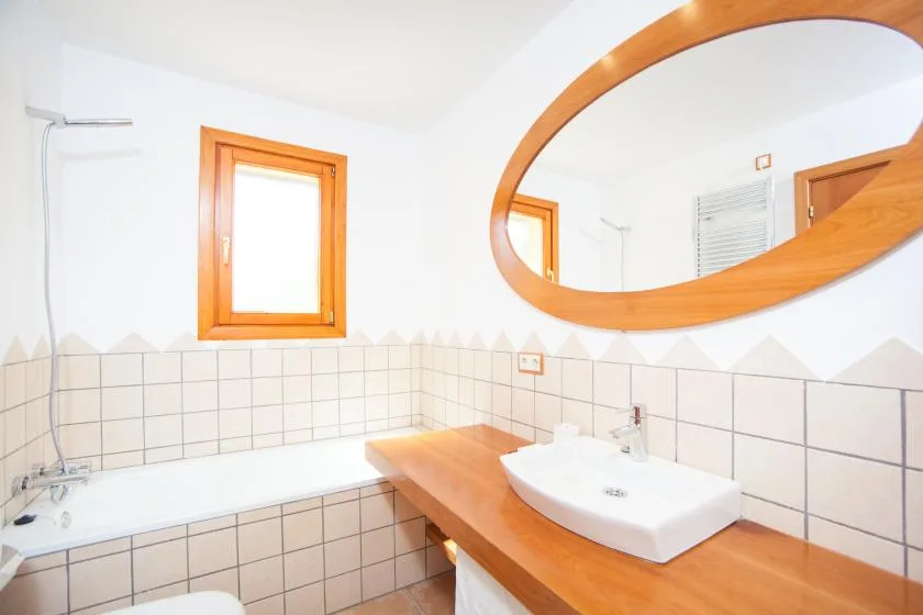 Un baño con bañera, lavabo y un gran espejo ovalado.