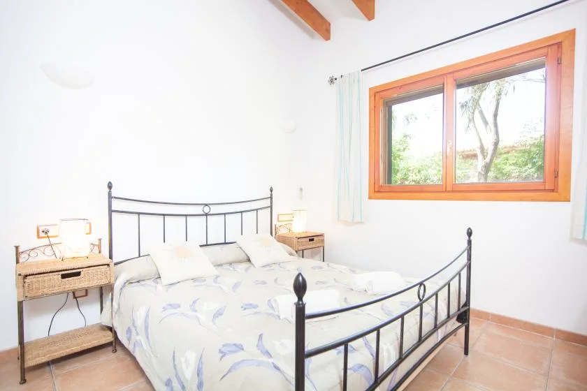 Un dormitorio luminoso con una cama junto a una ventana grande.