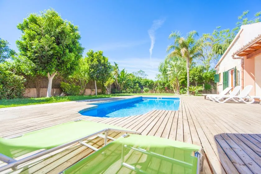 Una piscina al aire libre junto a una terraza de madera con asientos.