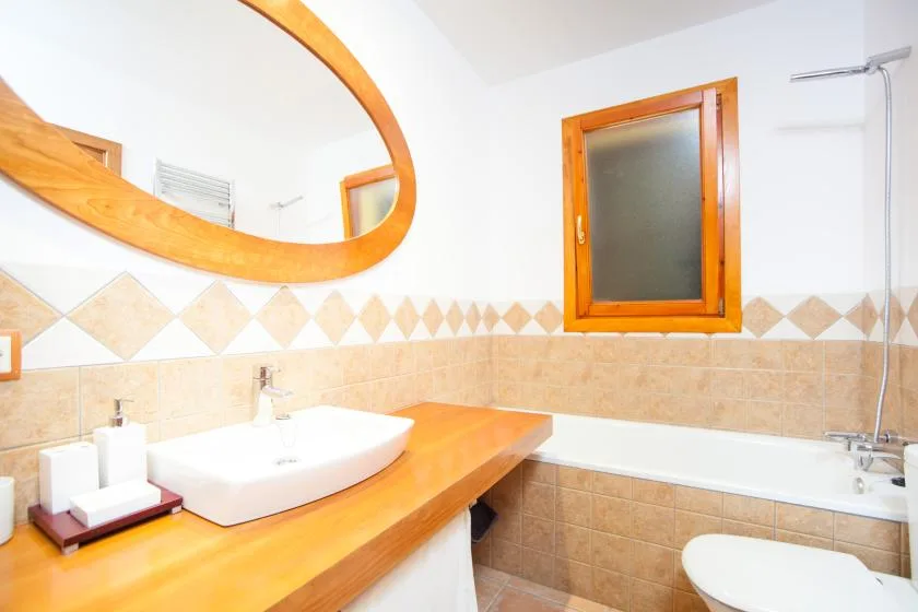Un baño con lavabo, bañera y una ventana con marco de madera.