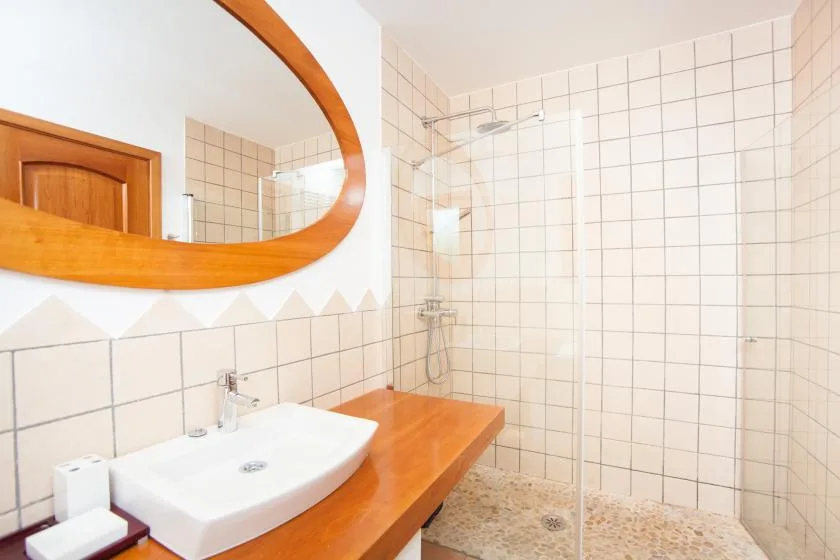 Un baño con azulejos tiene un lavabo blanco junto a una ducha de vidrio.