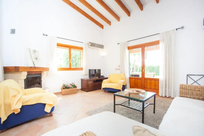 Una sala luminosa con asientos, una mesa de centro y puertas acristaladas con marcos de madera.