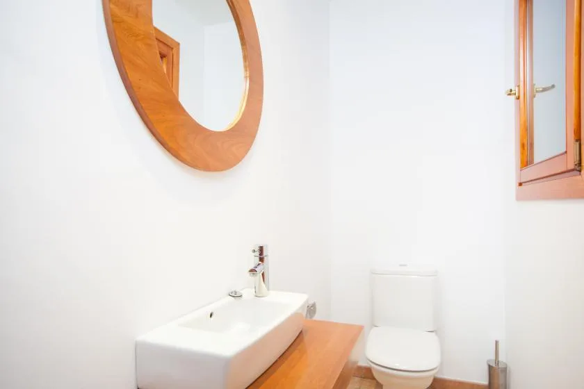 Un baño luminoso con lavabo, inodoro y espejo con marco de madera.