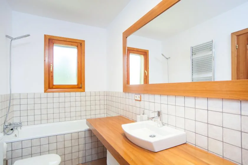 Un baño con azulejos, lavabo, bañera y un gran espejo en la pared.