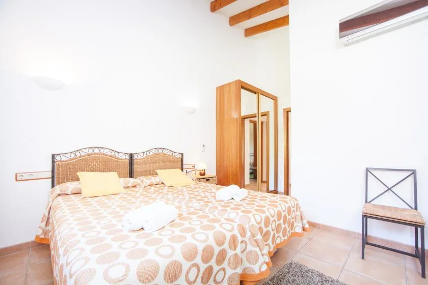 Un dormitorio luminoso con una cama, ropa de cama estampada y un armario de madera.