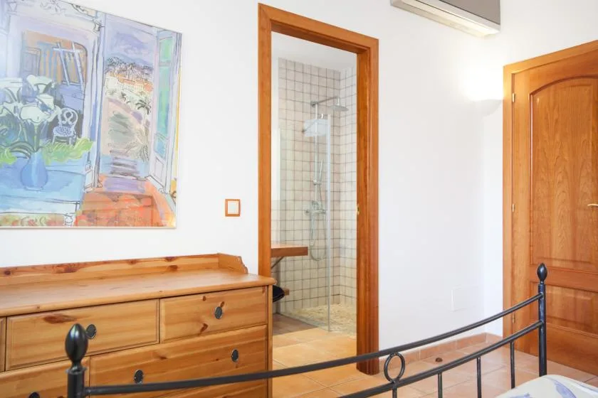 Un dormitorio con una cómoda de madera y una zona de ducha con azulejos.