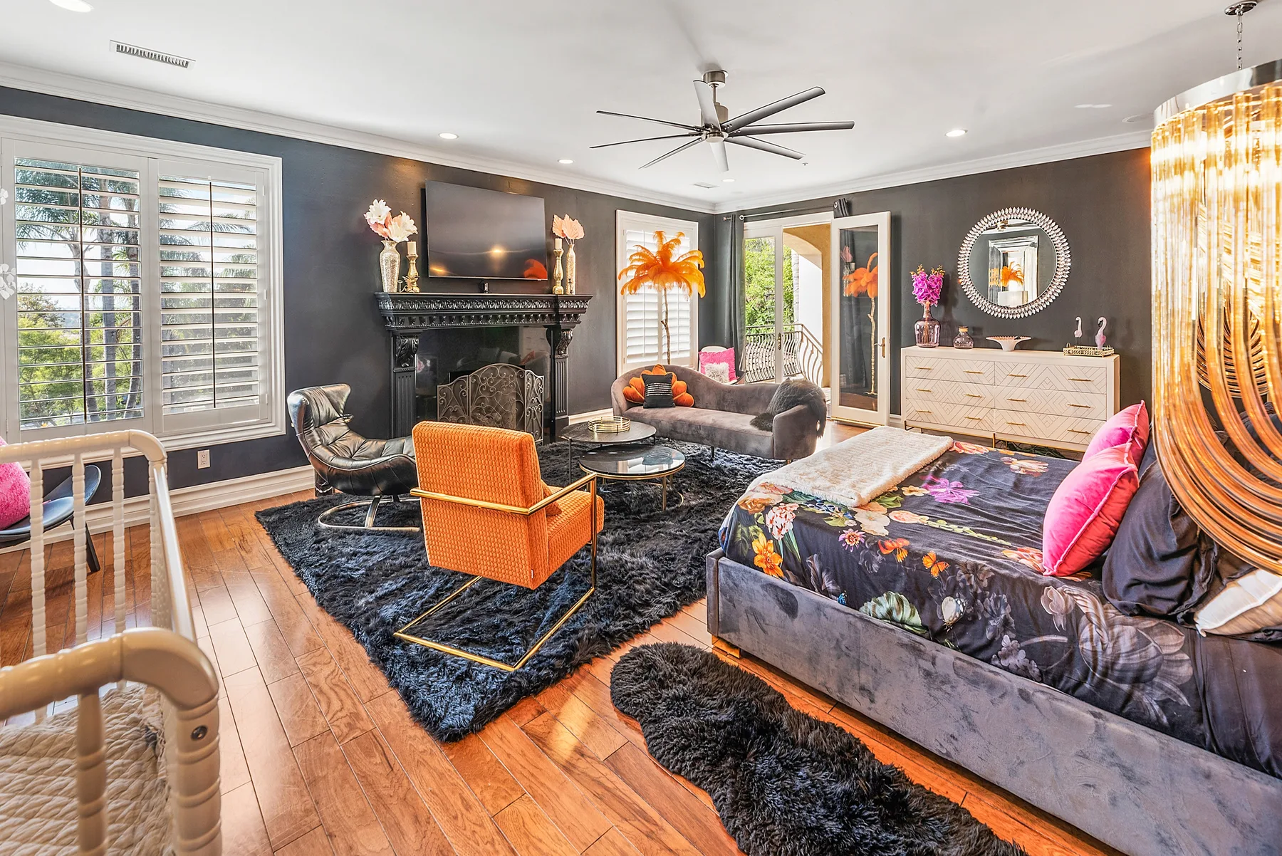 A dark-walled bedroom with a large bed, seating area, and fireplace.
