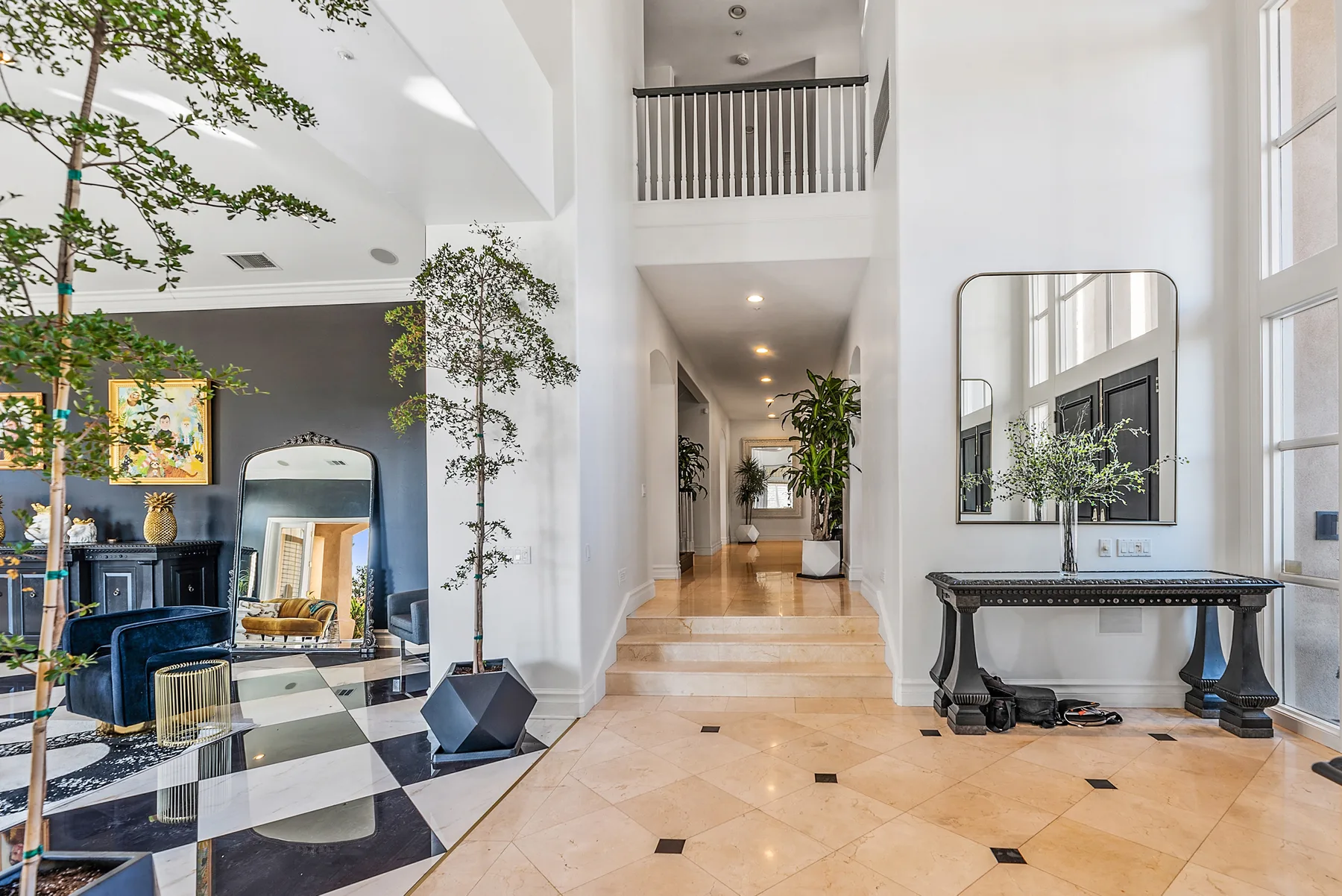 A bright double-height entry hall with a staircase and console table.