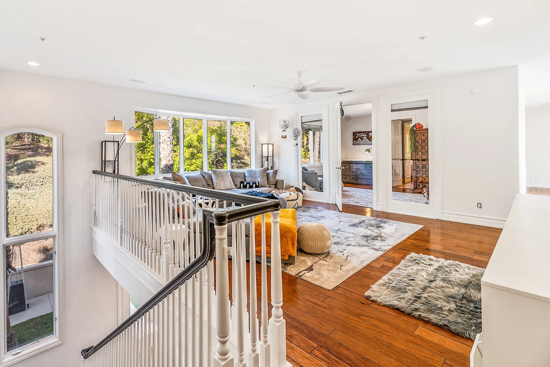 A bright upstairs living area opens onto a carpeted landing with hardwood floors.