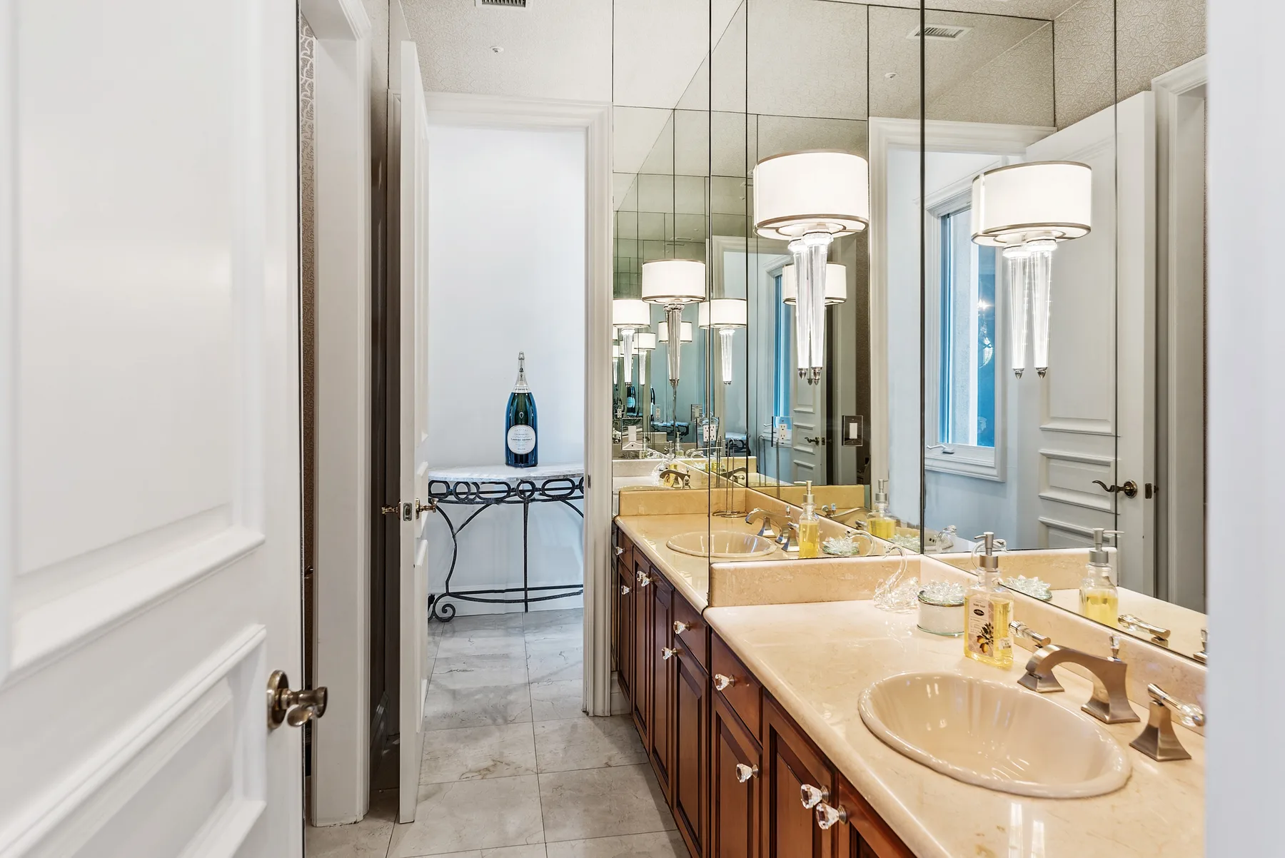 A bright bathroom with a long counter, sinks, and large mirrors.