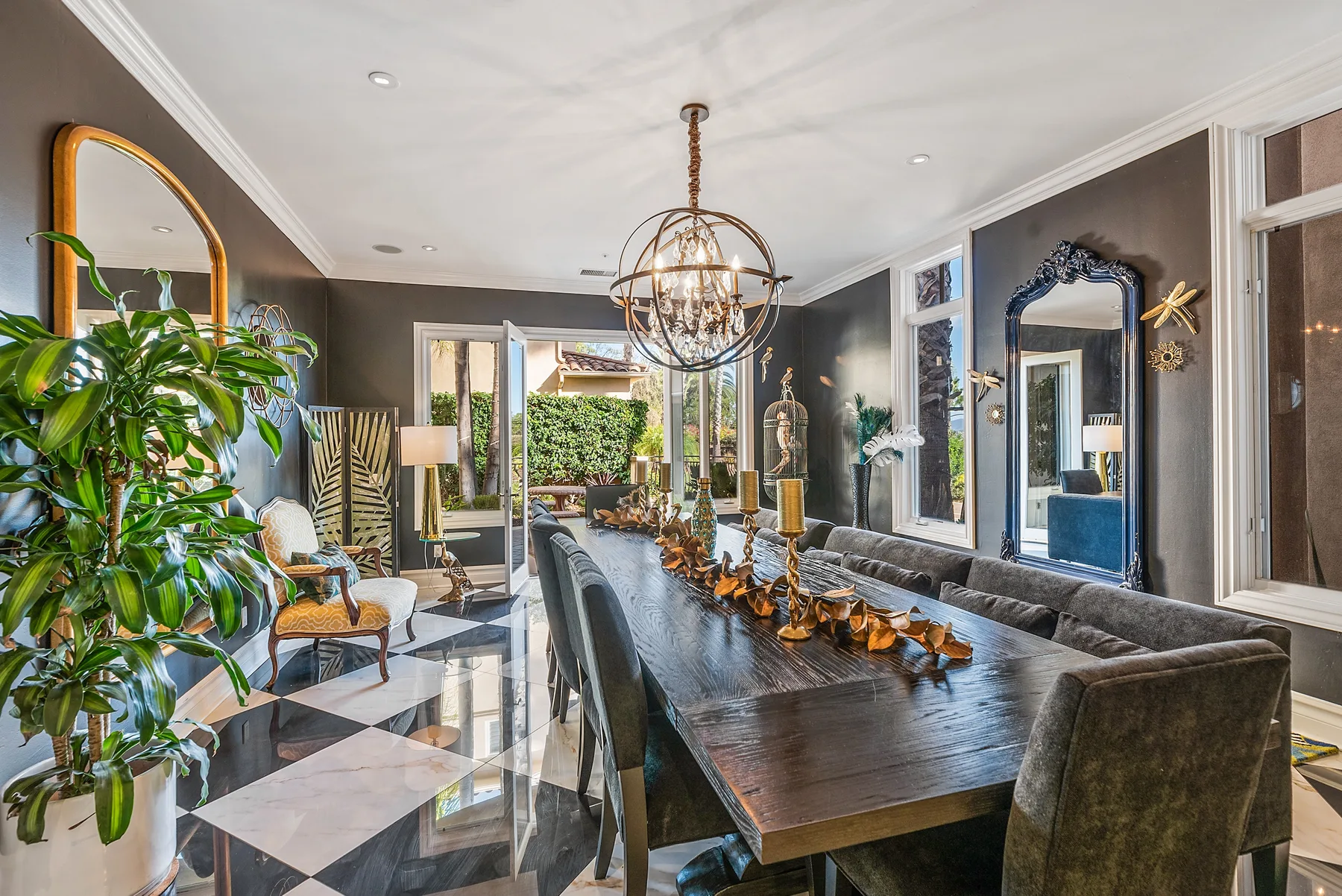 A dining room with a long table, upholstered seating, and a chandelier.