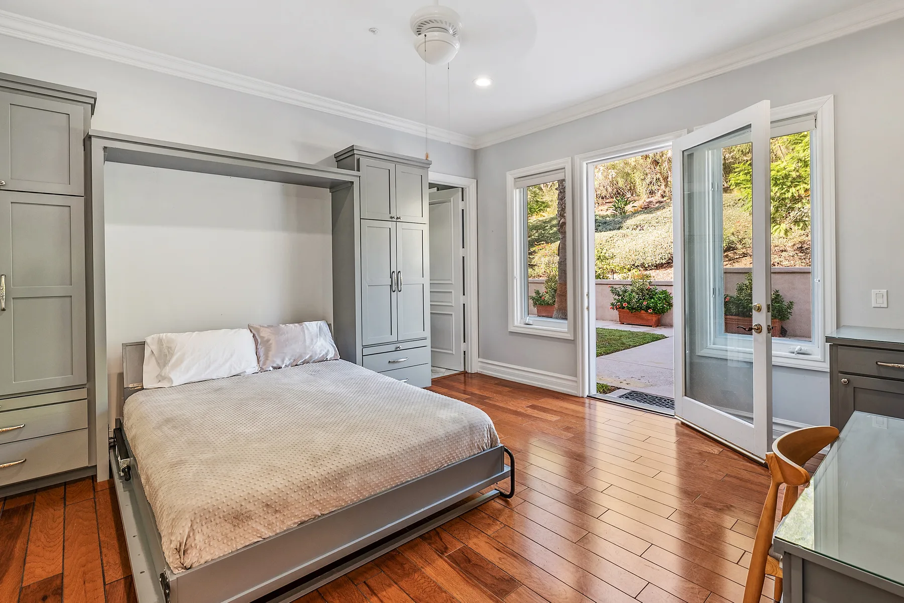 A bedroom with a bed and open glass doors leading to a garden.