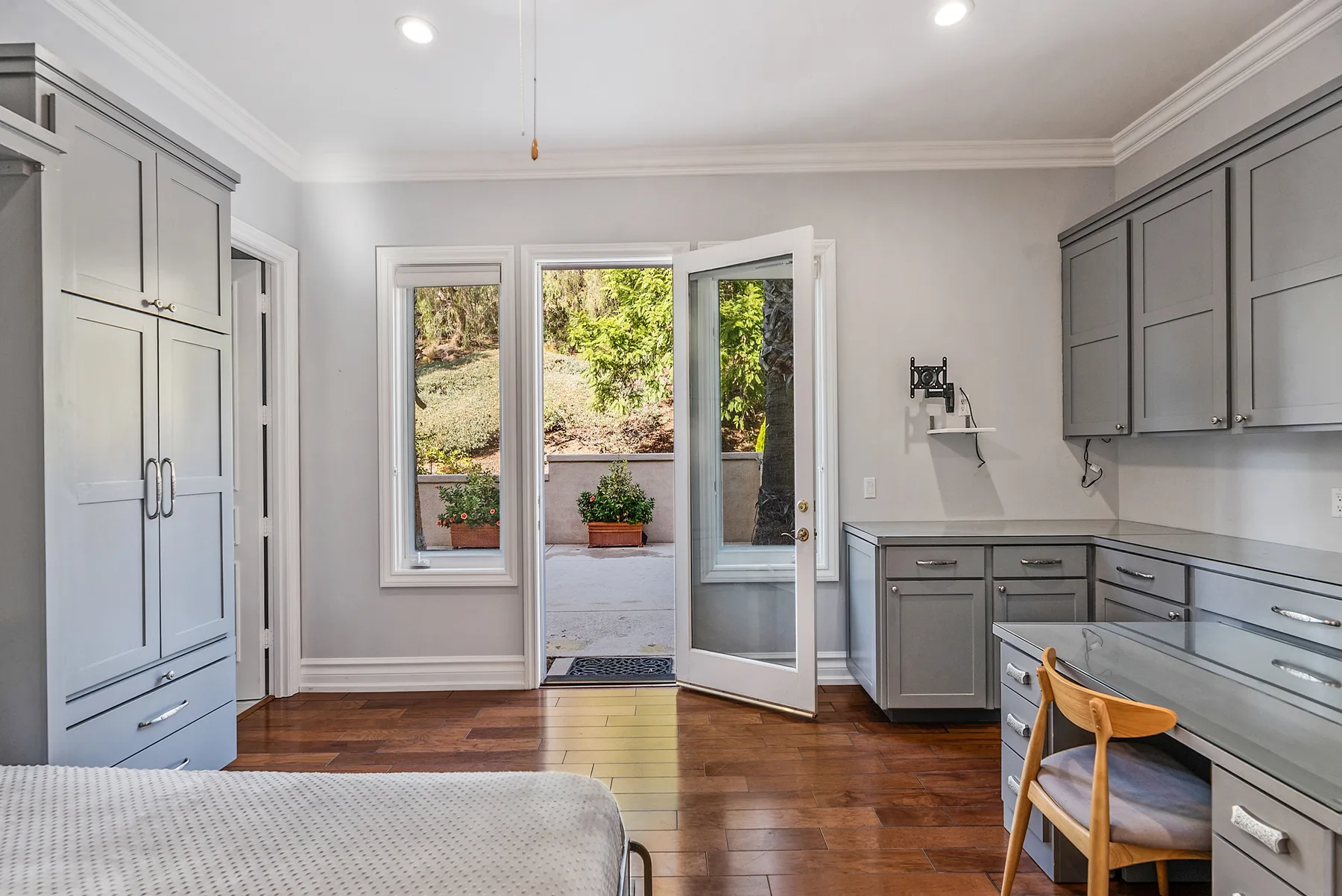 A bright room with built-in cabinets, a desk, and an open door to the patio.