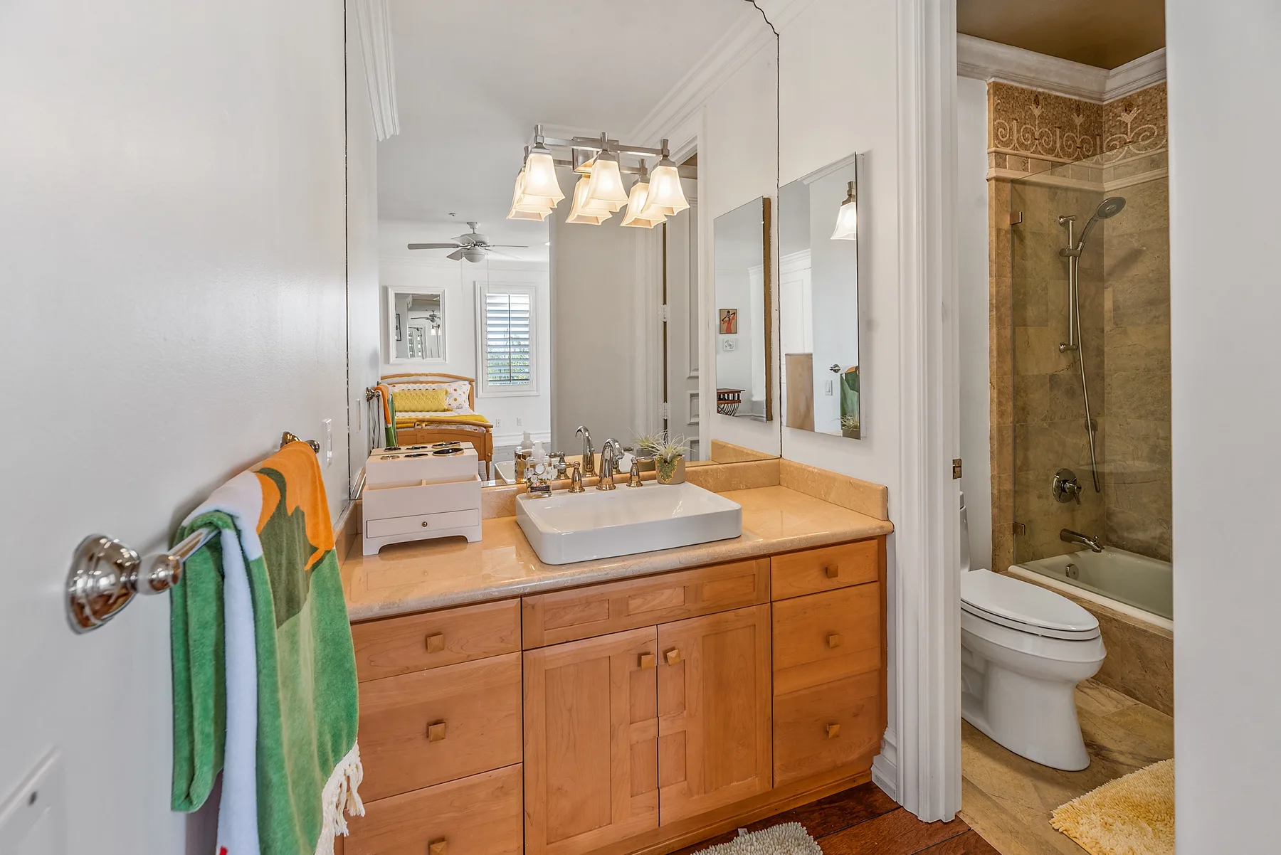 A bright bathroom with a wooden vanity, sink, and shower.