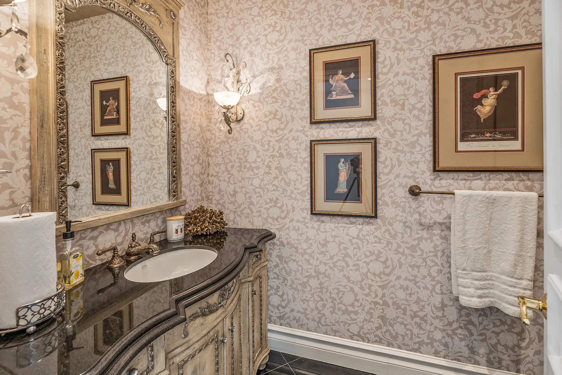 A bathroom vanity with a sink and framed artwork on patterned walls.