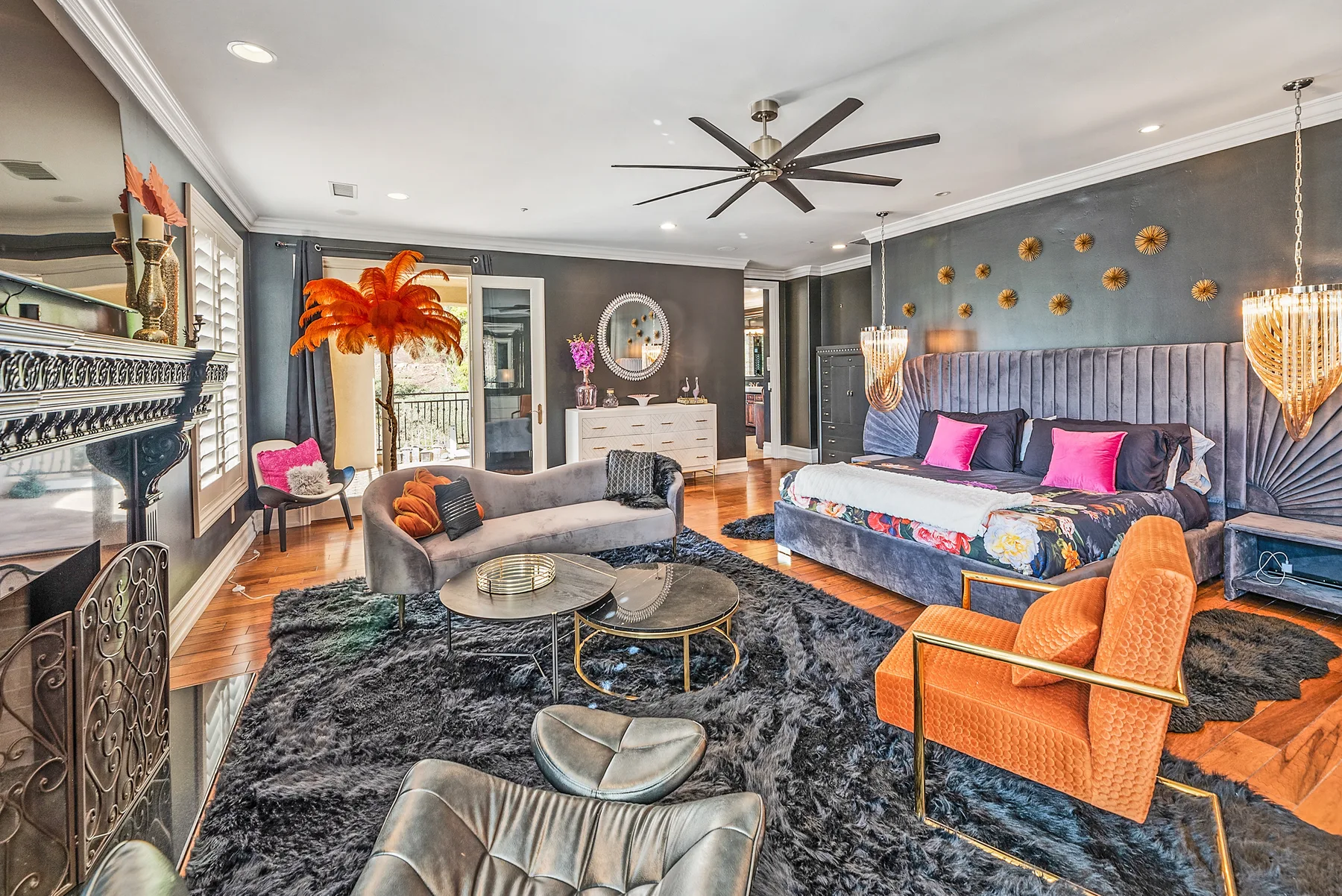 A bedroom with a large bed, lounge seating, and a dark area rug.